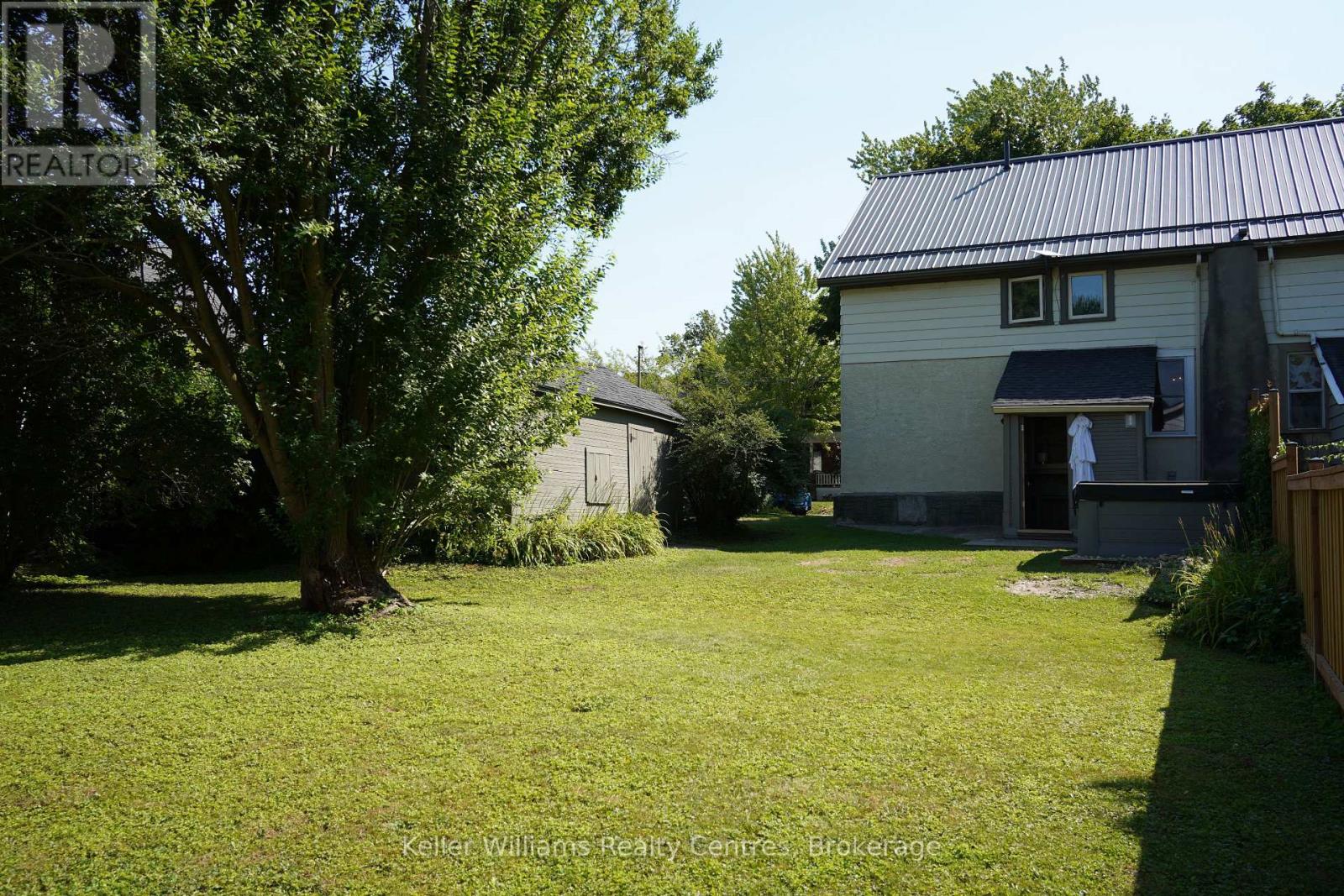 Deep, shaded backyard at 96 Charles Street with mature trees and metal-roofed garage